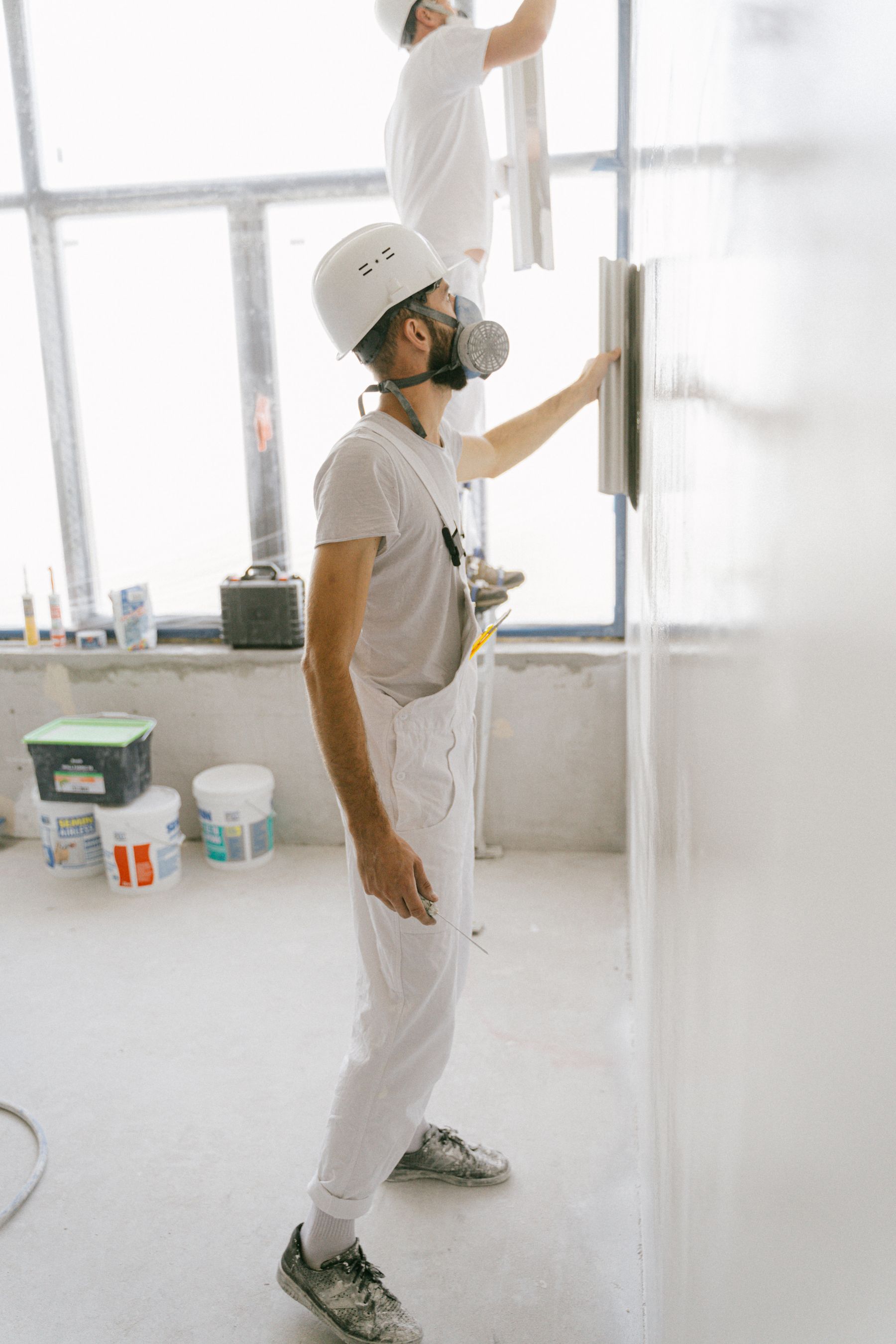 Two drywall finishers applying joint compound to an interior wall